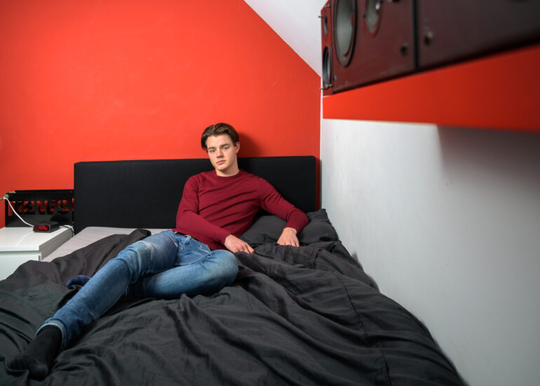 Tiener jongen zittend op bed